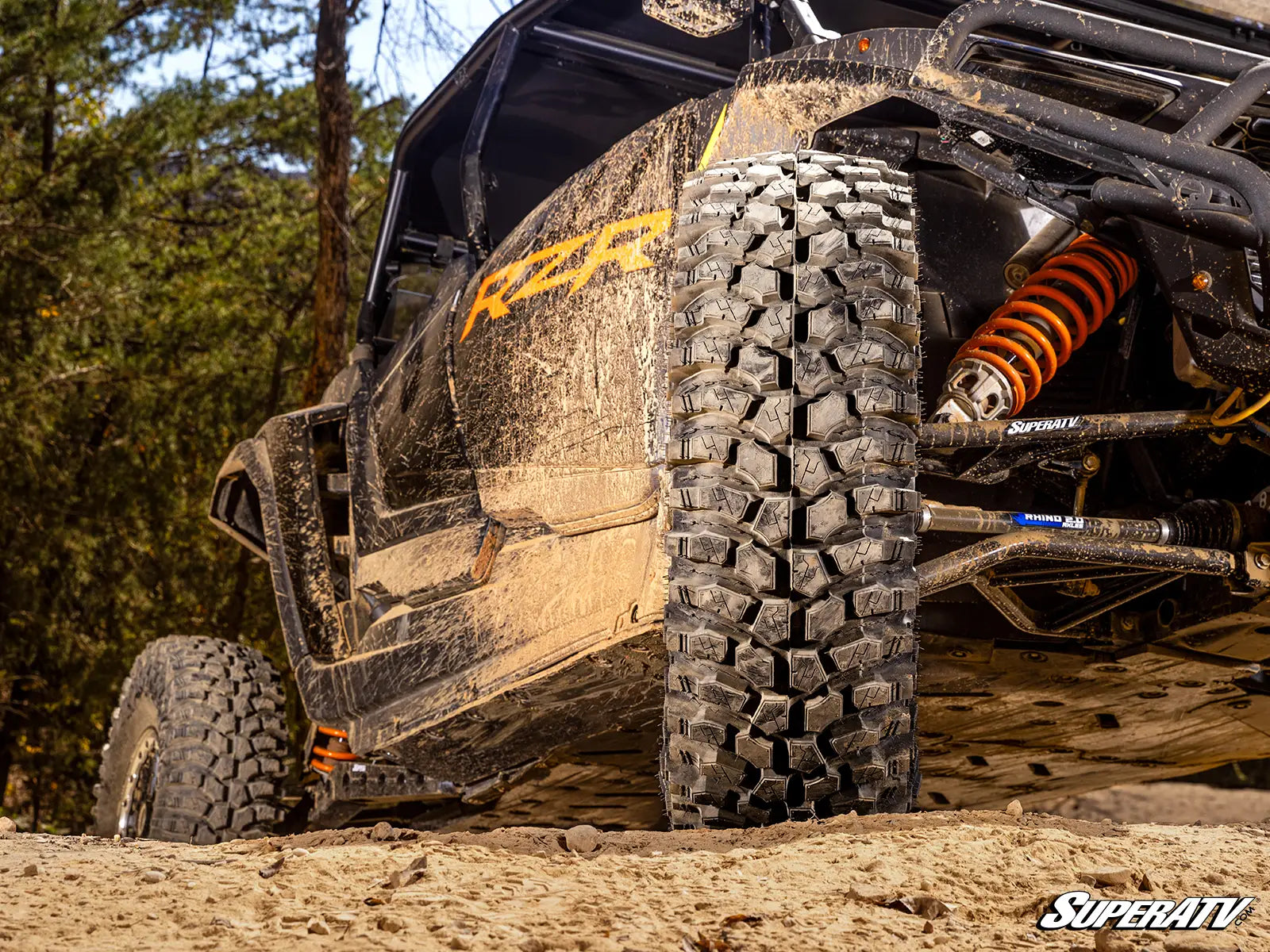 Off-road vehicle with large tires on a dirt path, featuring SuperATV branding.
