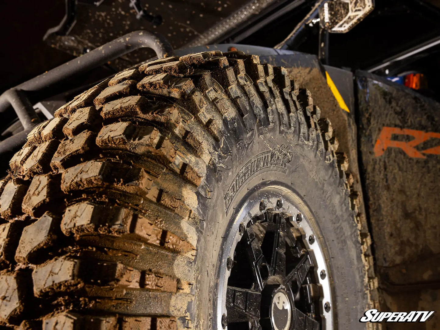 Close-up of a mud-covered tire with tread pattern on a SuperATV vehicle.