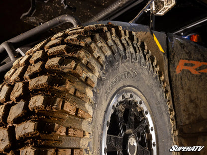 Close-up of a mud-covered tire with tread pattern on a SuperATV vehicle.