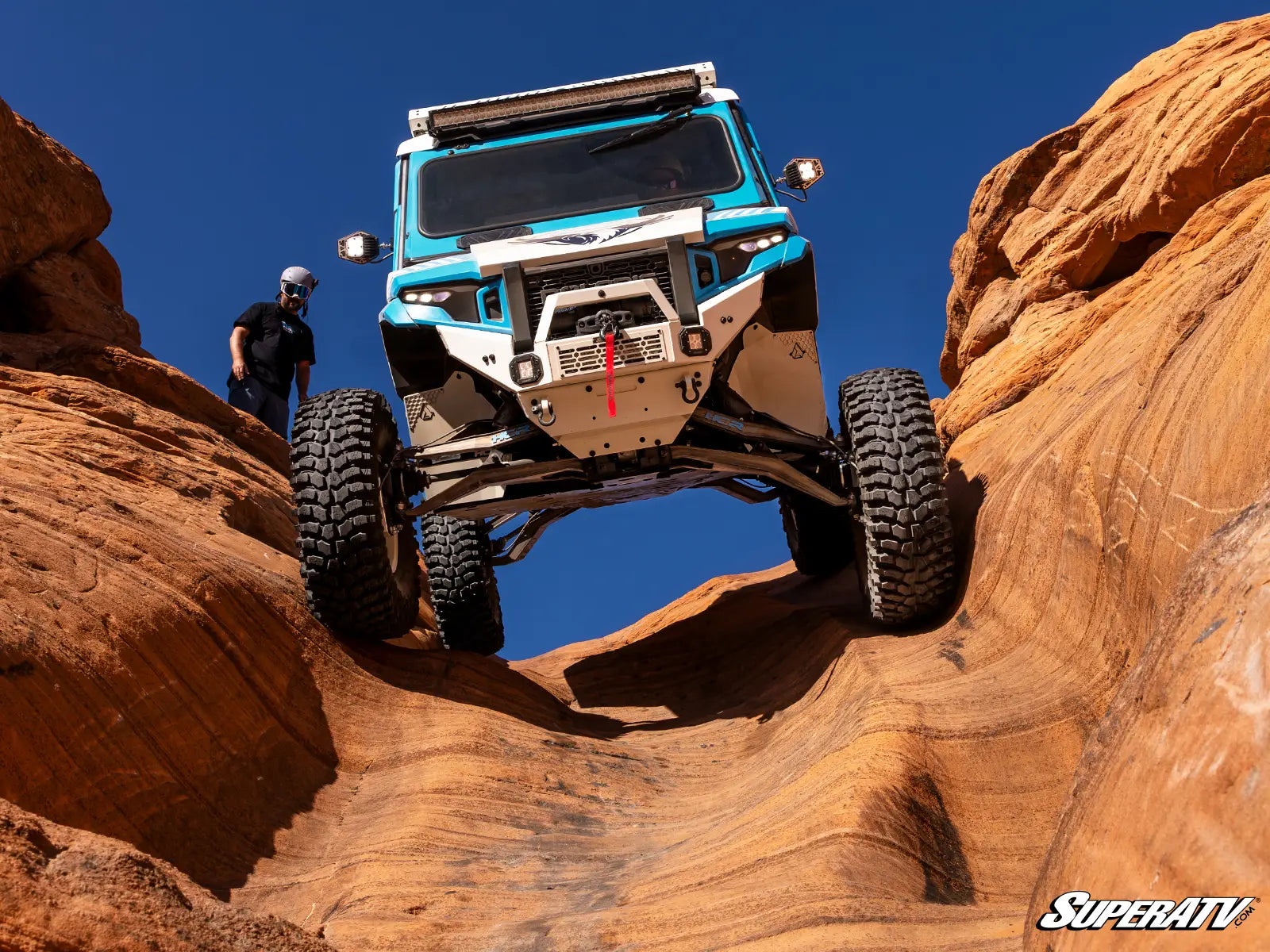 Off-road vehicle navigating rocky terrain with 'SuperATV' branding.
