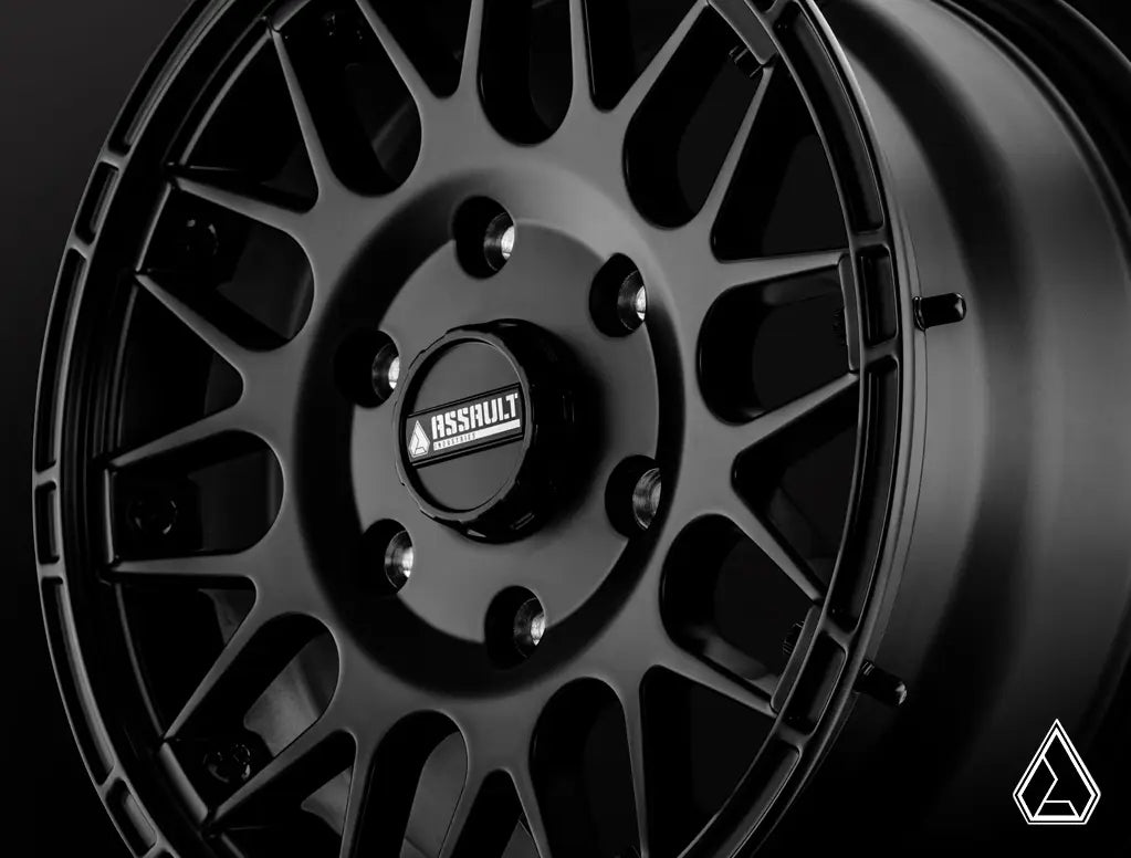 Close-up of a black alloy wheel with a brand logo on a dark background