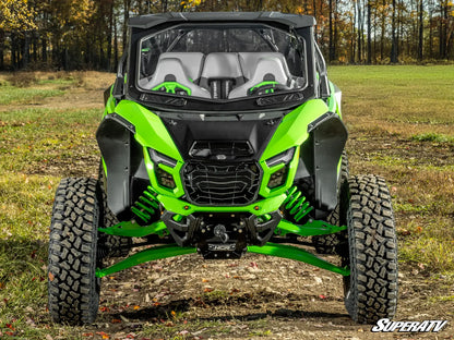 Green and black SuperATV vehicle in a field with trees in the background