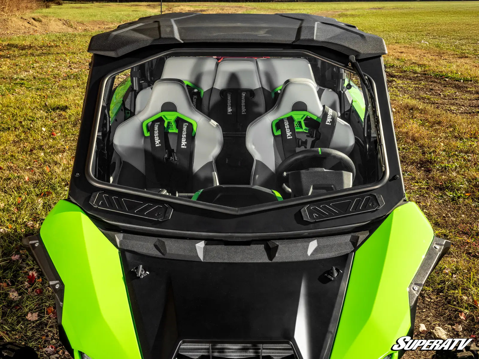 Green and black SuperATV vehicle with open top in a field