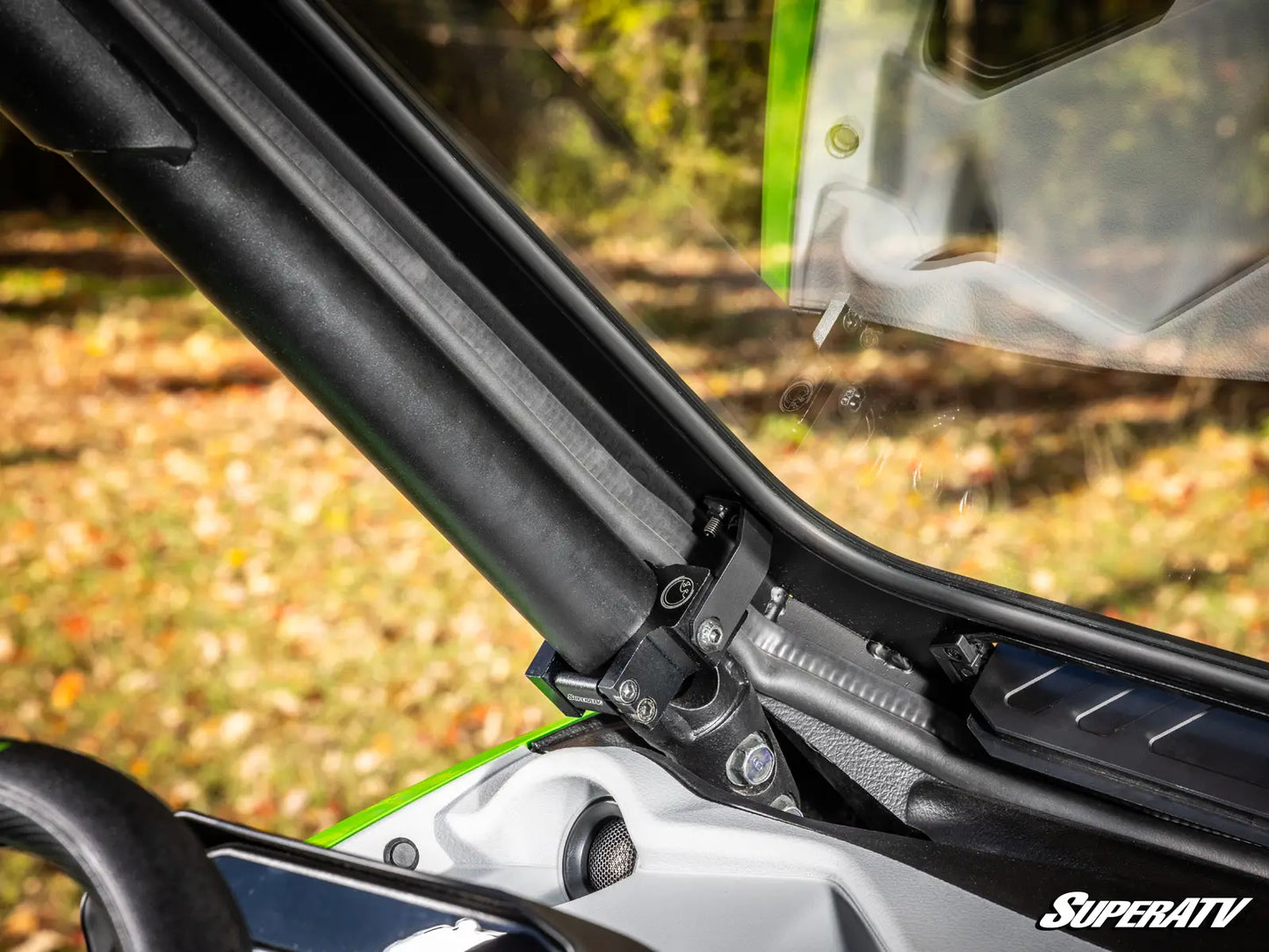 Close-up of a vehicle's windshield wiper mechanism with a blurred natural background