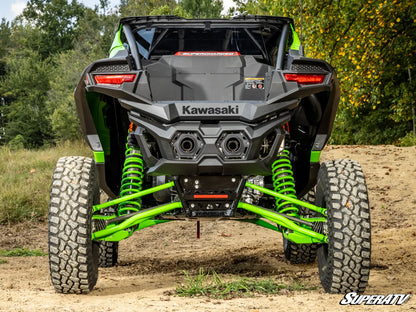 Kawasaki ATV with green suspension on a dirt path with trees in the background