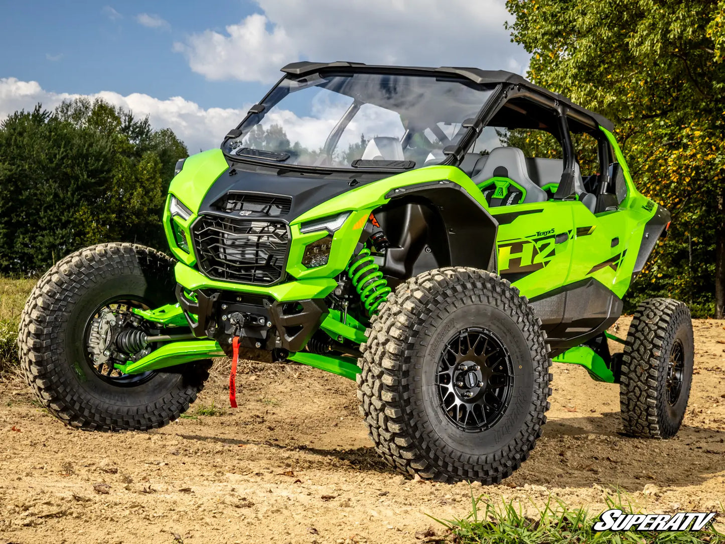 Green off-road vehicle on a dirt path with trees in the background