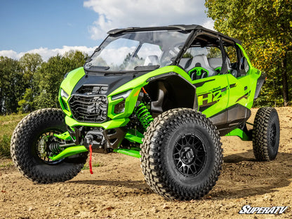 Green off-road vehicle on a dirt path with trees in the background