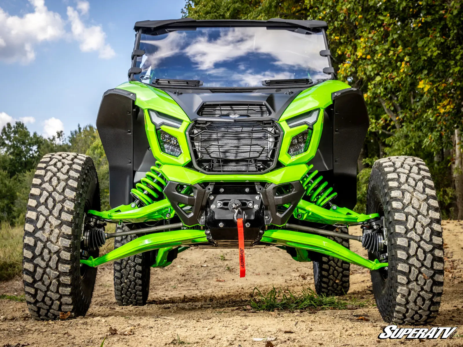 Green off-road vehicle on a dirt path with trees in the background