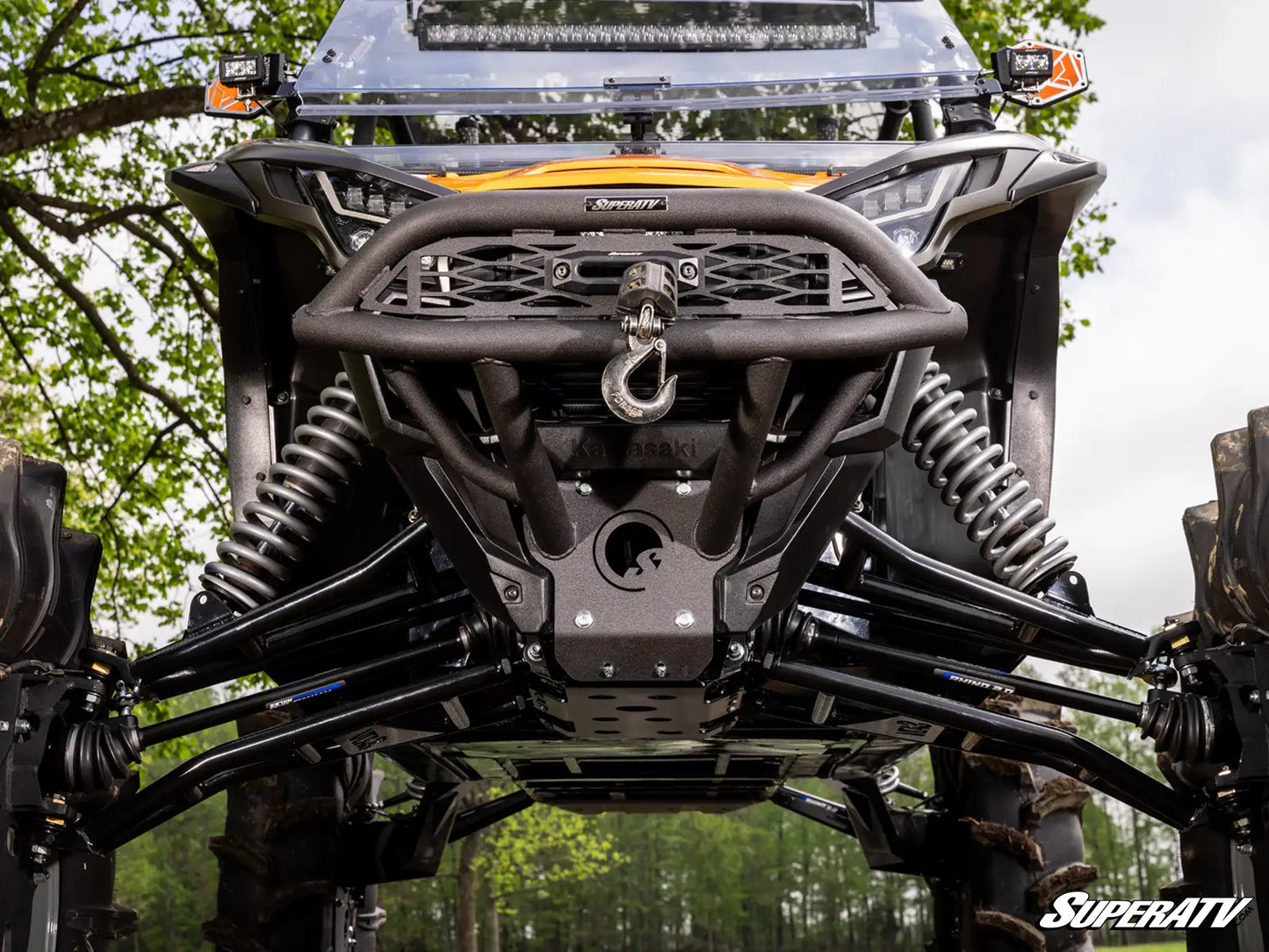 Close-up of an off-road vehicle with a SuperATV logo in a forest setting