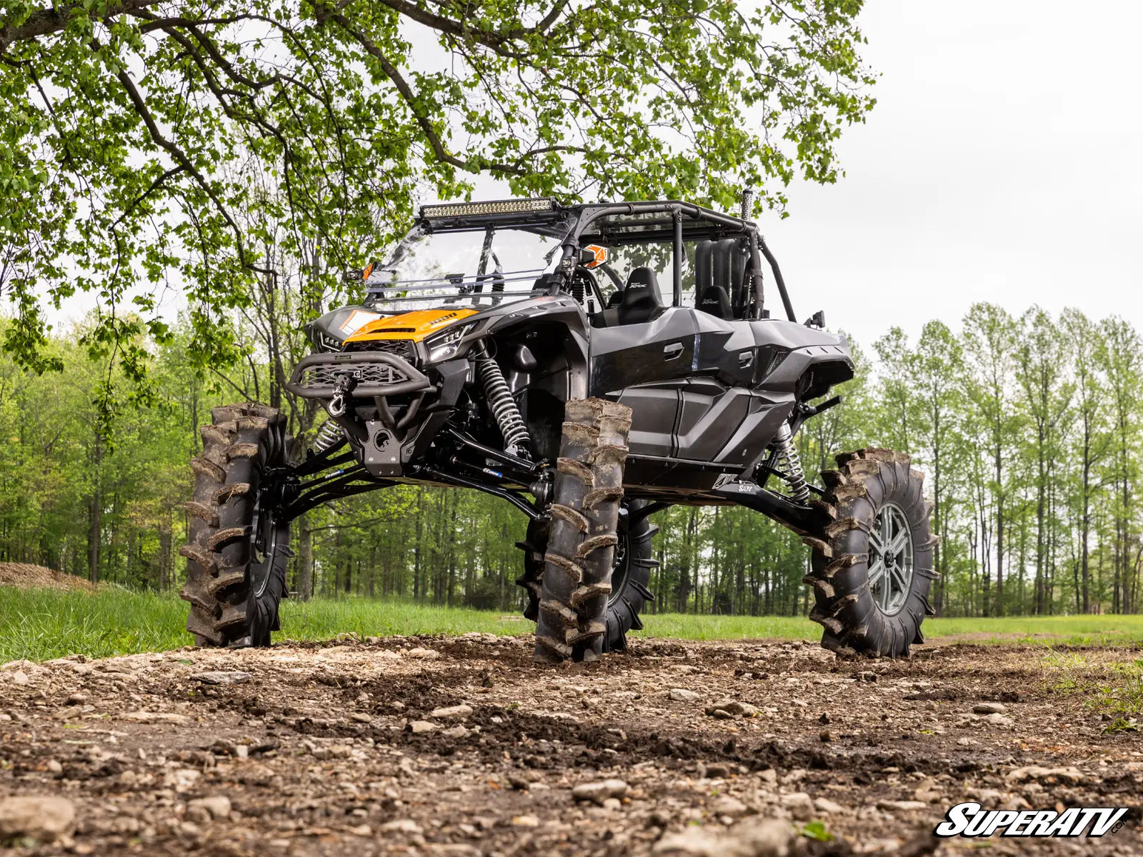 SuperATV off-road vehicle on a dirt path with trees in the background