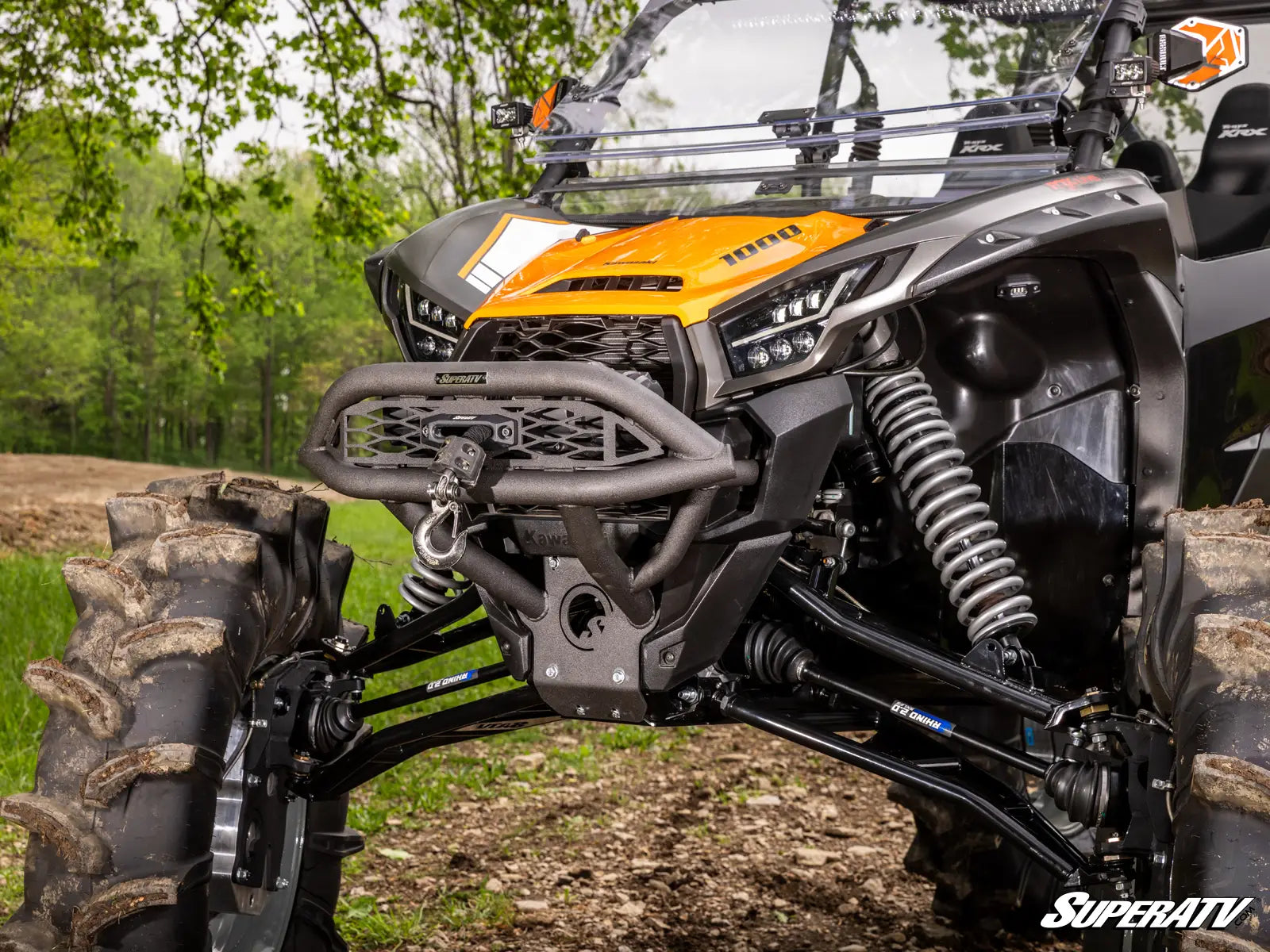 SuperATV off-road vehicle with detailed suspension and front bumper in a forest setting