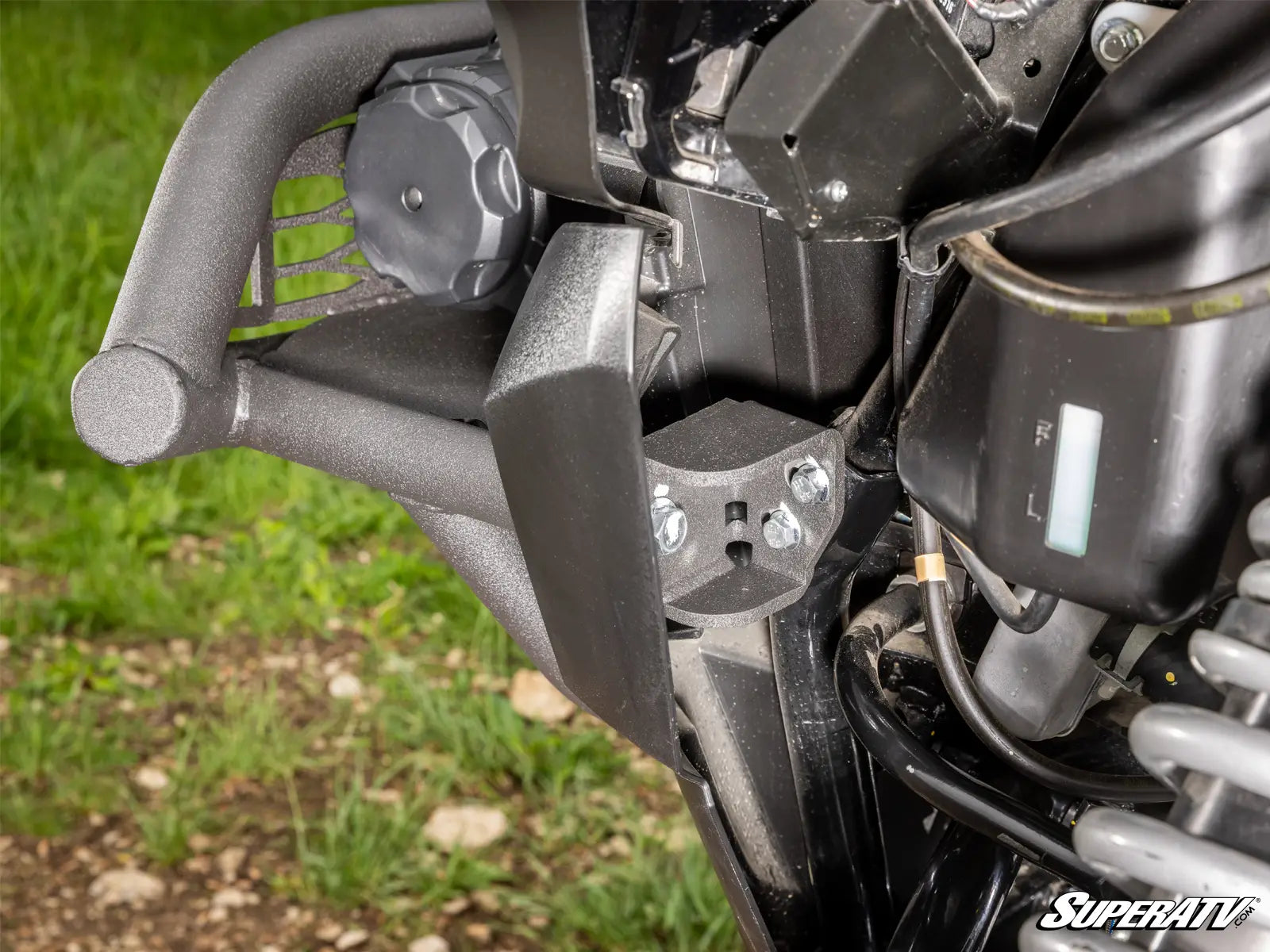 Close-up of a motorcycle's front suspension system with grass in the background