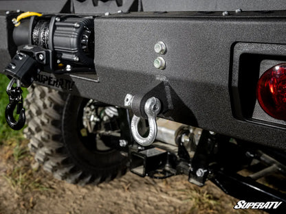 Close-up of a SuperATV vehicle bumper with hooks and lights on a grassy background
