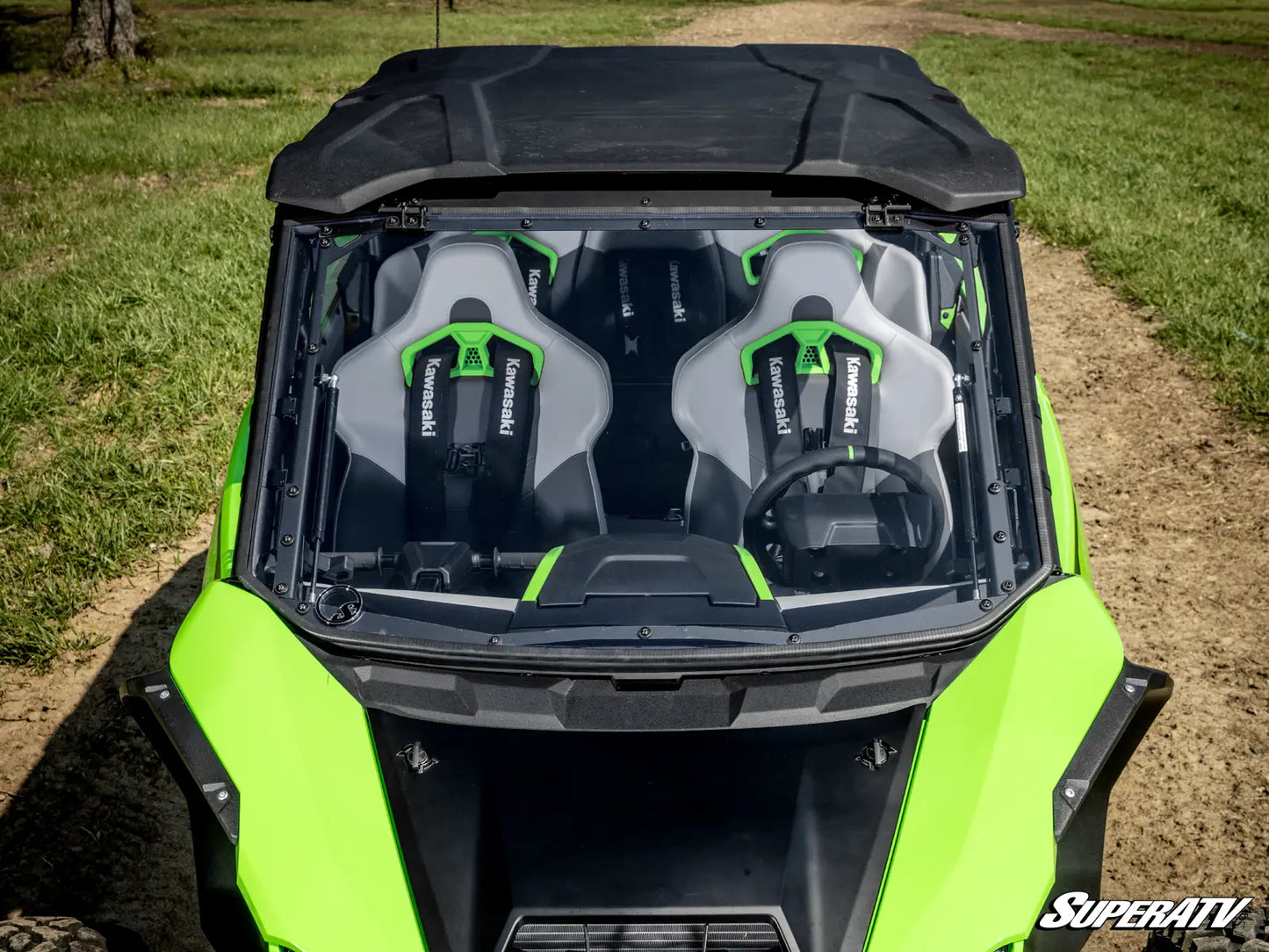 Green and black off-road vehicle with open roof showing two seats on a grassy field.