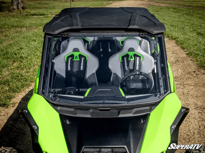 Green and black off-road vehicle with open roof showing two seats on a grassy field.