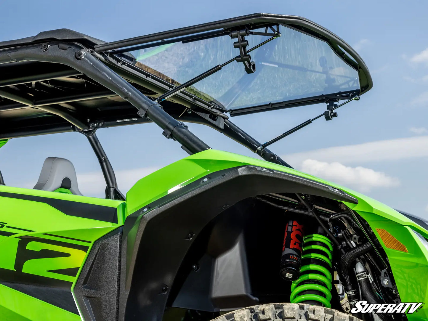 Green off-road vehicle with open canopy against a blue sky