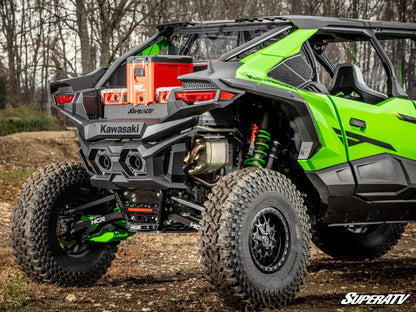 Green Kawasaki SuperATV vehicle on a dirt path with trees in the background