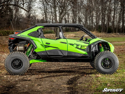 Green and black off-road vehicle on a dirt path with trees in the background