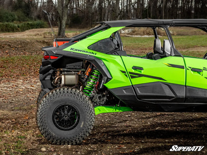 Green Kawasaki SuperATV vehicle on a dirt path with trees in the background