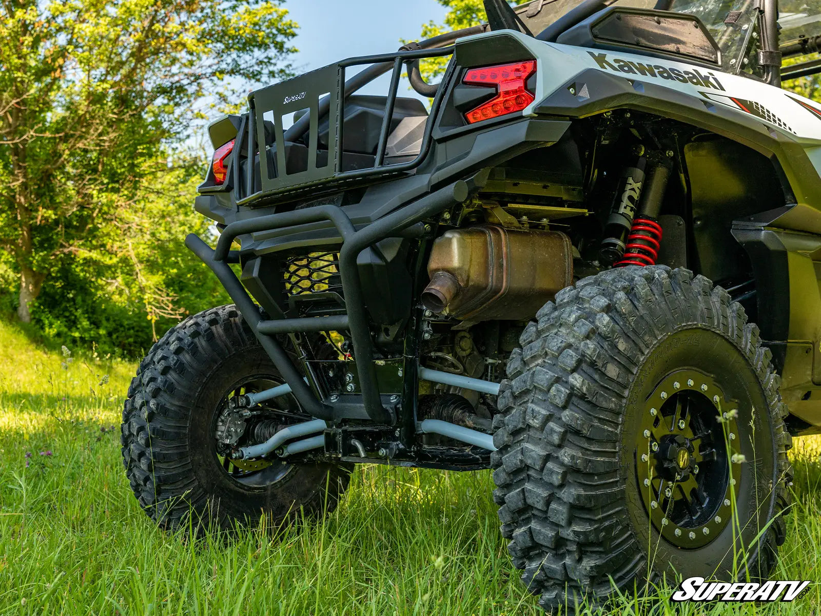 Kawasaki ATV in a grassy outdoor setting with trees in the background