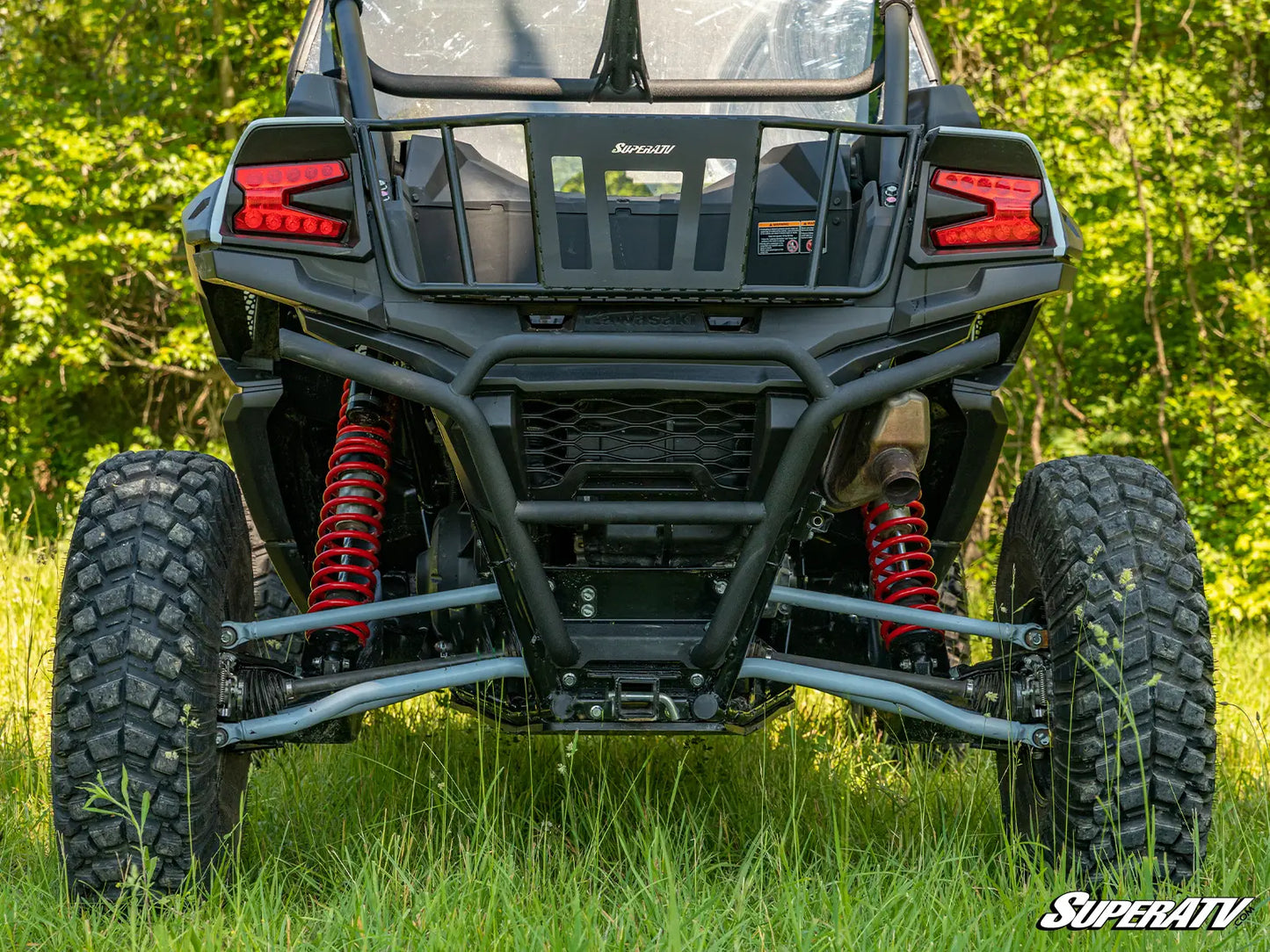 Off-road vehicle with red suspension springs in a grassy area, featuring the SuperATV logo.