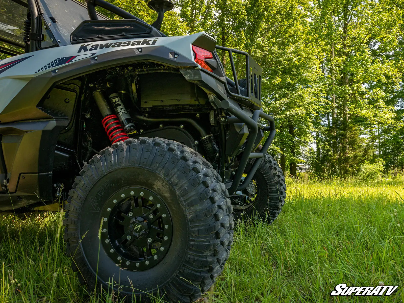 Kawasaki ATV in a grassy field with trees in the background