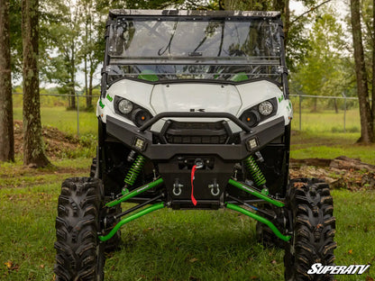 White UTV with green suspension on a grassy area with trees in the background