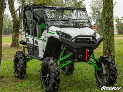 White and green off-road vehicle with large wheels in a wooded area