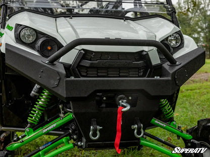 Close-up of a SuperATV vehicle with green suspension and black front bumper on grass.