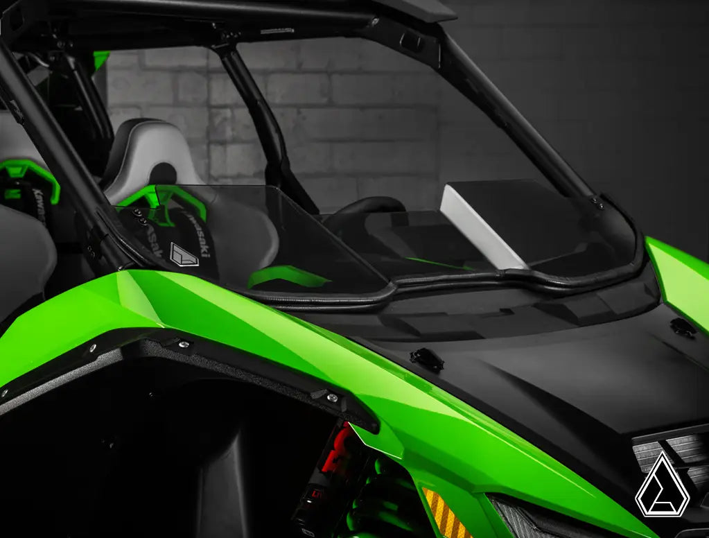 Green and black off-road vehicle with a clear windshield in a dark setting
