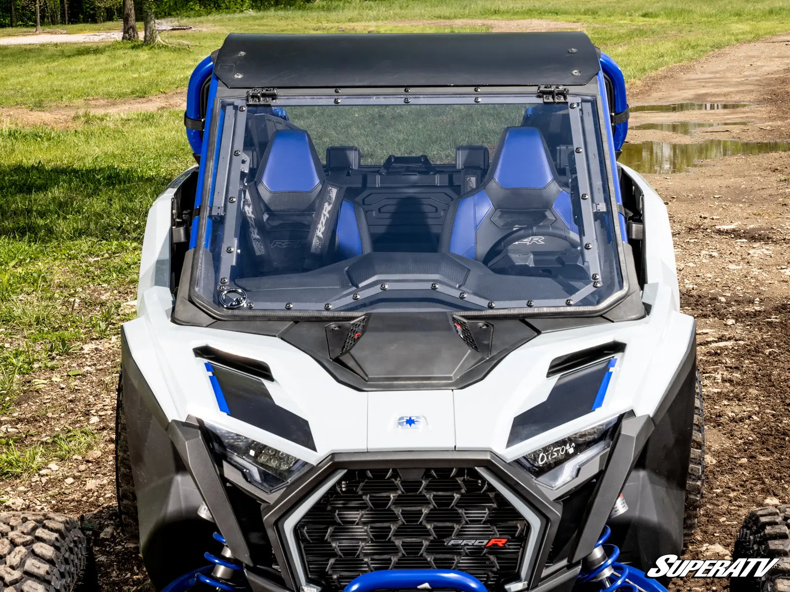 White and blue off-road vehicle with transparent roof on a dirt path
