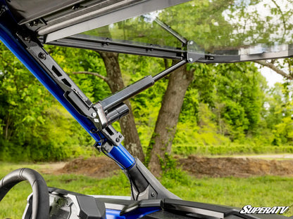 Close-up of a SuperATV vehicle with an open roof in a forest setting