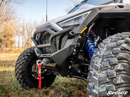 Close-up of an off-road vehicle with large tires and suspension components in a natural setting.