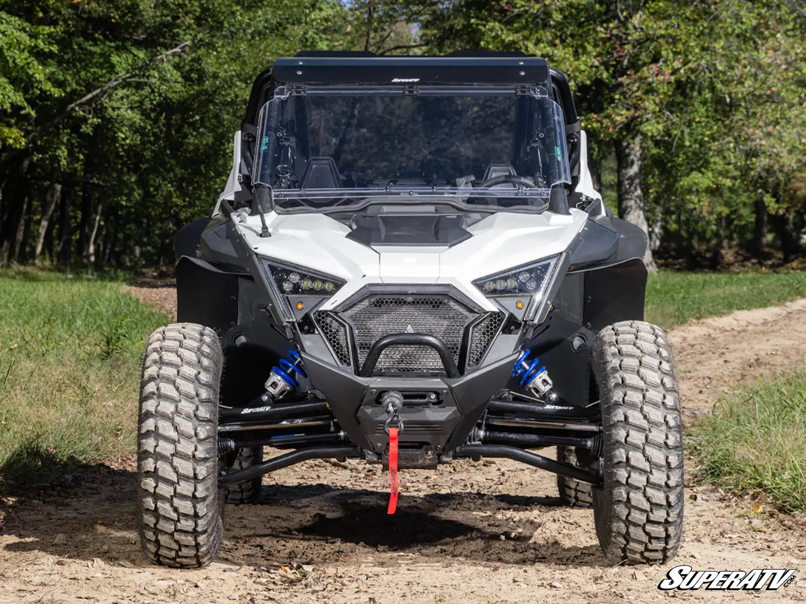 Side-by-side vehicle on a dirt path with trees in the background