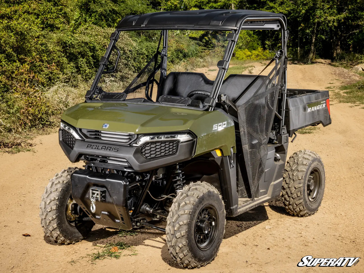 Green Polaris SuperATV vehicle on a dirt road with trees in the background