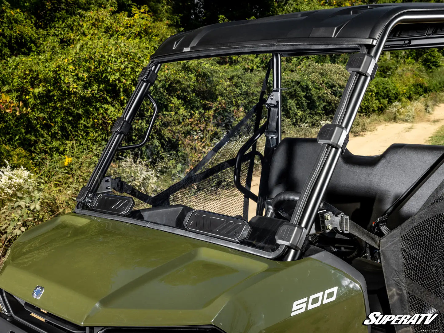 Green UTV with a black roof and SuperATV branding in a natural setting.