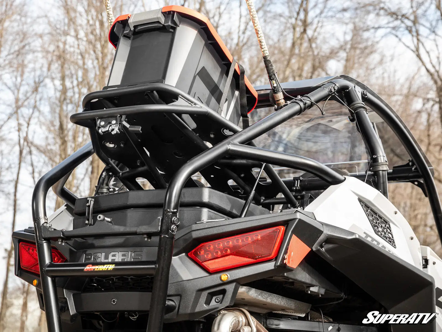 Side view of a Polaris SuperATV vehicle with a clear windshield in a forest setting.