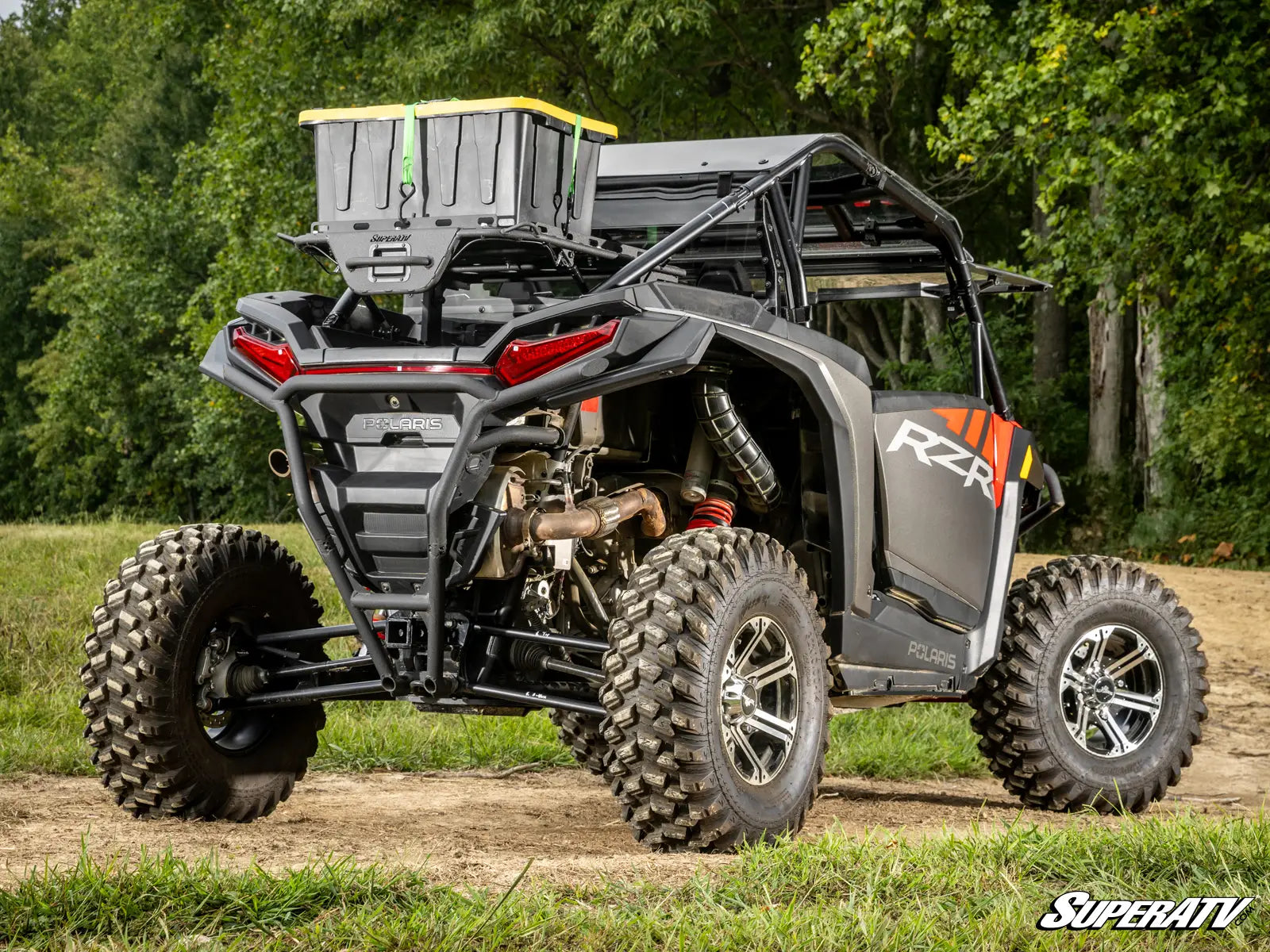 SuperATV off-road vehicle on a dirt path with trees in the background