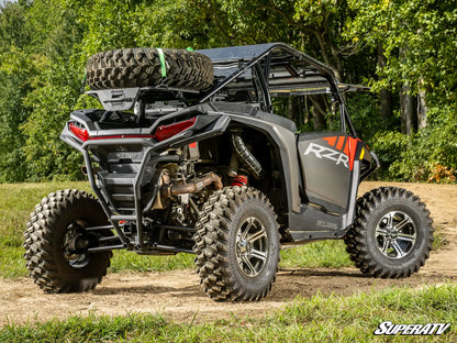 Off-road vehicle with large tires on a dirt path surrounded by trees