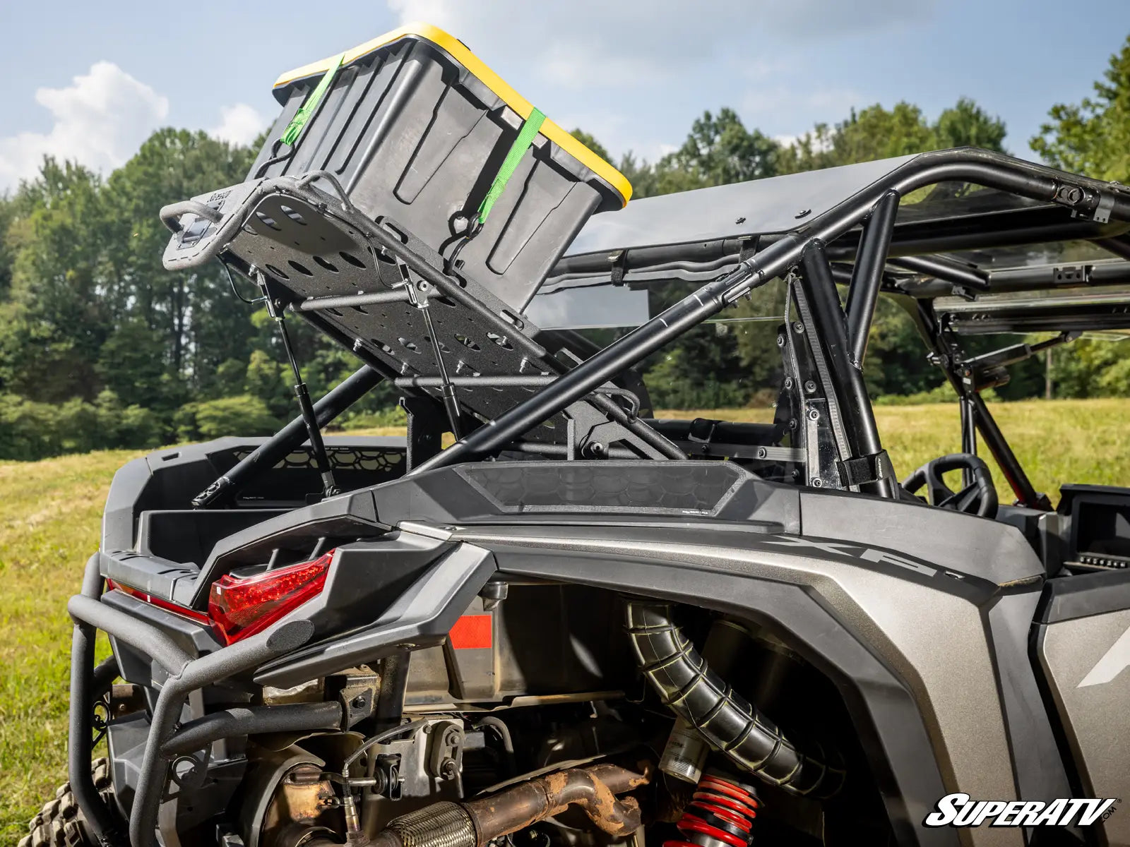 Side view of a SuperATV vehicle with storage rack and equipment on a grassy field.