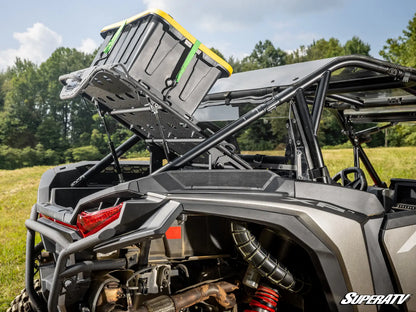 Side view of a SuperATV vehicle with storage rack and equipment on a grassy field.