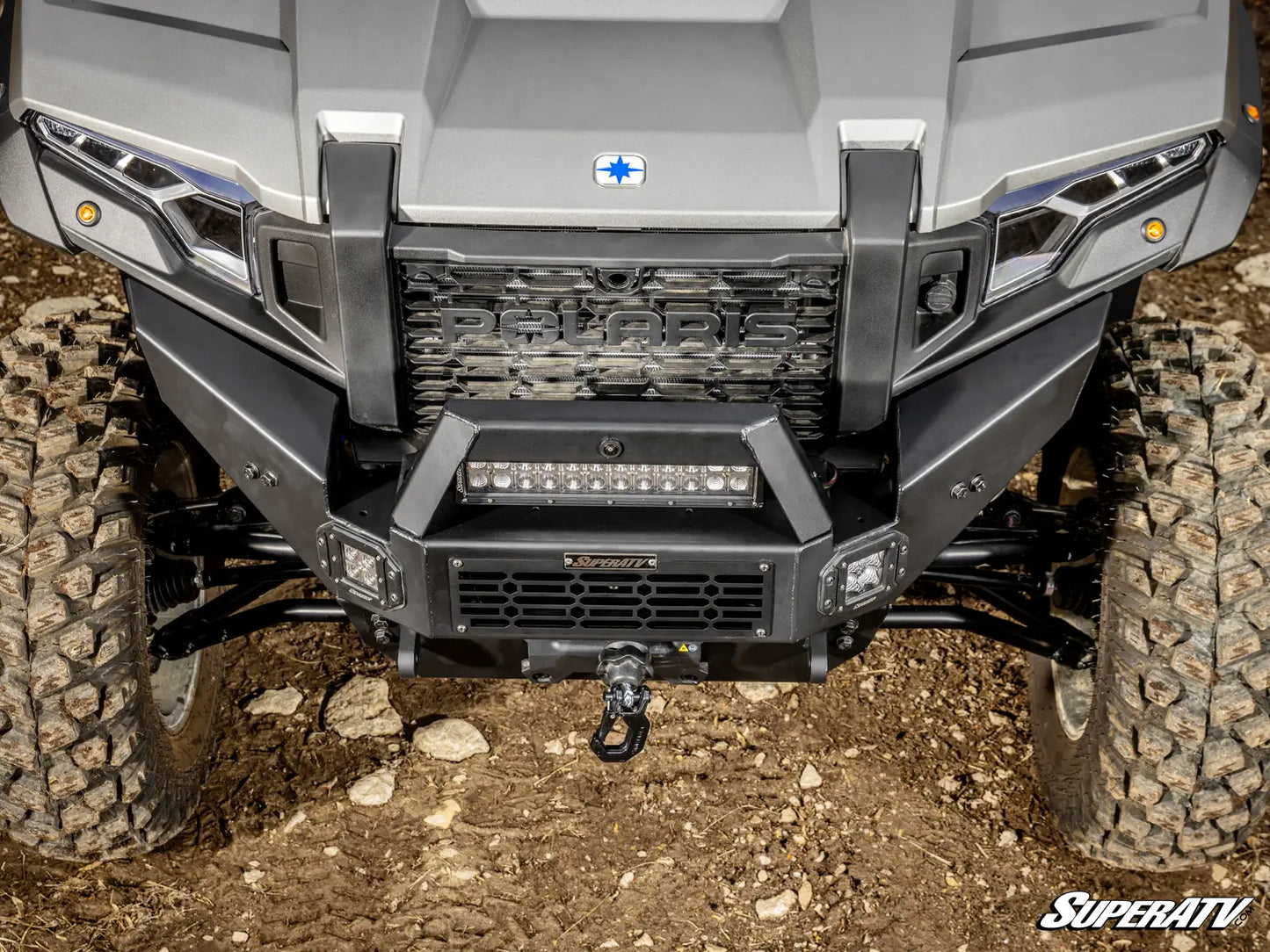 Close-up of a Polaris ATV front bumper with visible branding on a dirt surface.