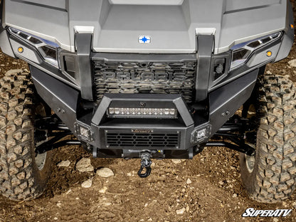 Close-up of a Polaris ATV front bumper with visible branding on a dirt surface.