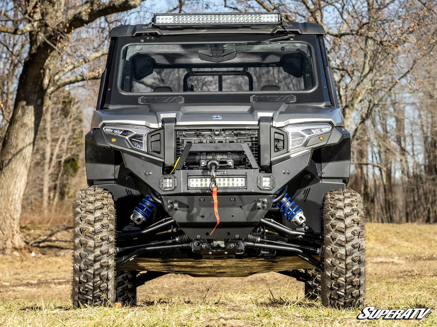 Off-road vehicle with a SuperATV logo in a forest setting