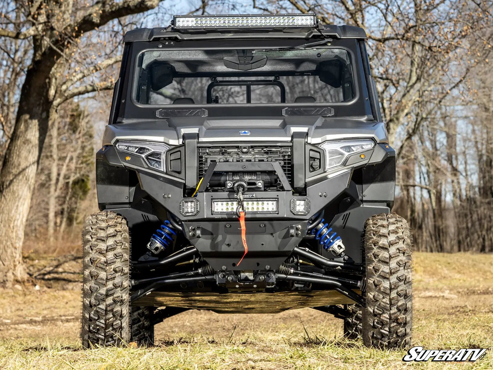 Off-road vehicle with a SuperATV logo in a forest setting