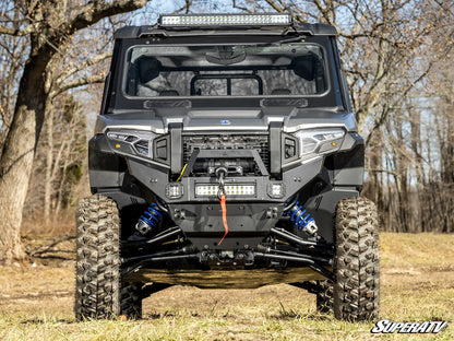 Off-road vehicle with a SuperATV logo in a forest setting