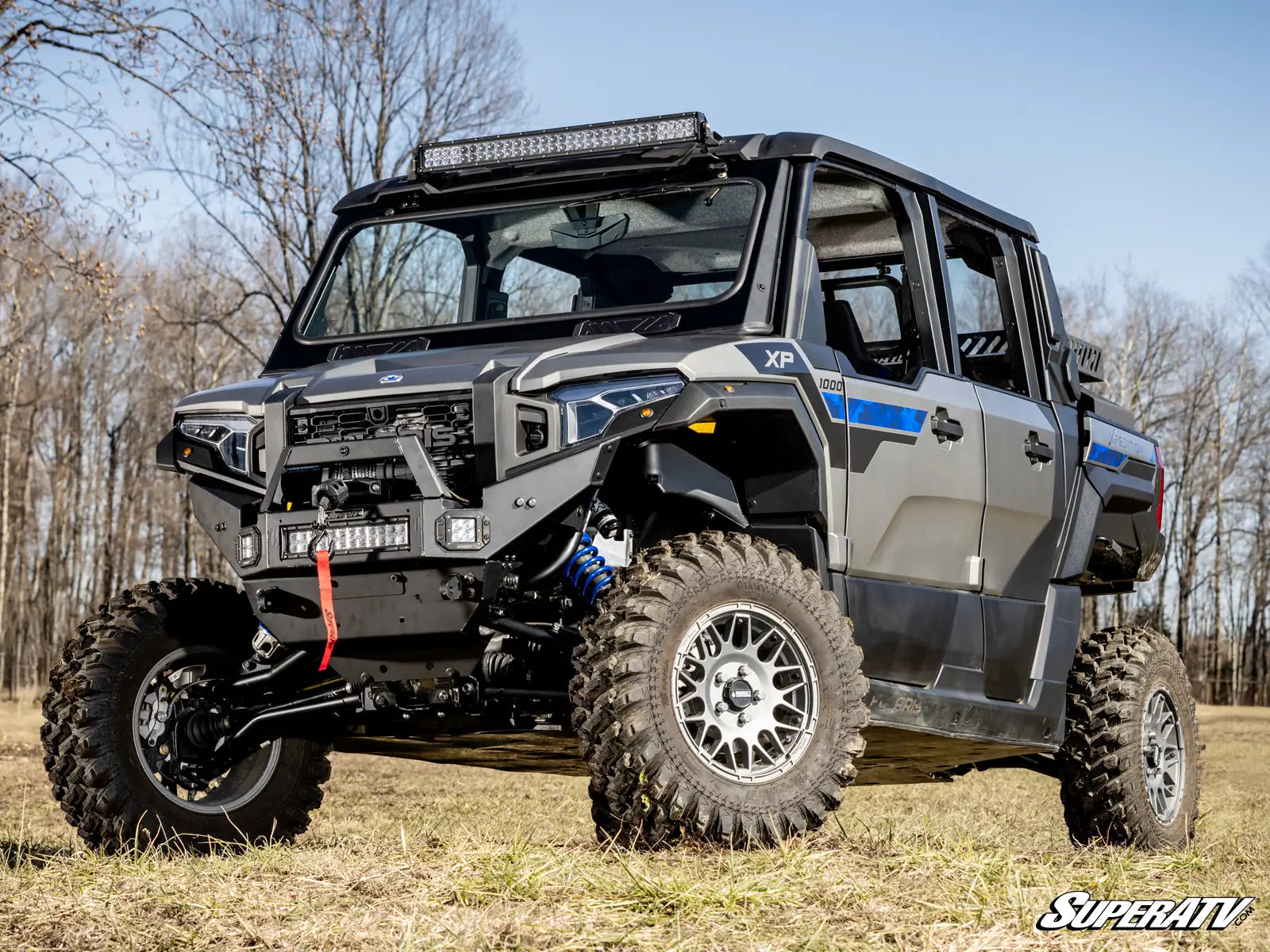 Off-road vehicle with large tires in a grassy field with trees in the background