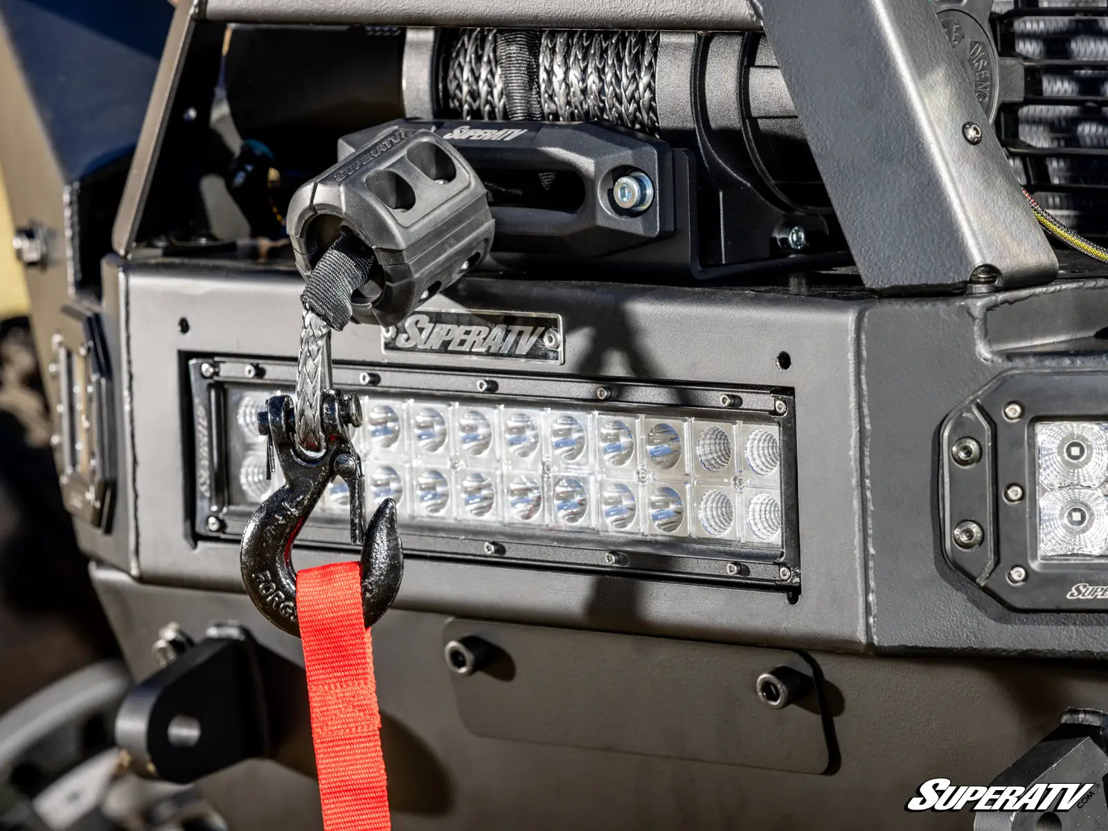Close-up of a vehicle winch with SuperATV branding and LED lights.