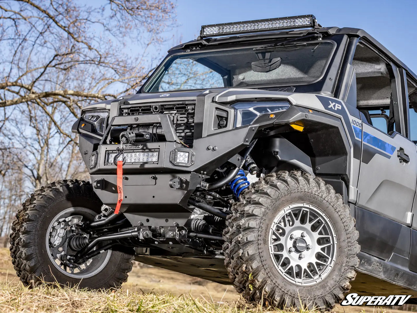 Off-road vehicle with large tires and visible SuperATV branding on a grassy area.