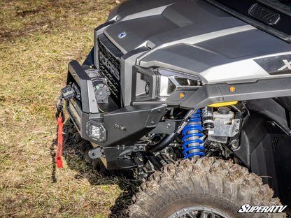 Close-up of an off-road vehicle with suspension system on a grassy surface, featuring SuperATV branding.